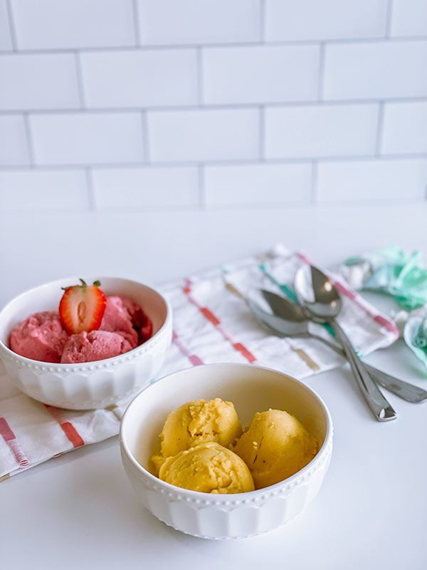 A bowl of strawberry and a bowl of mango "nice" cream.